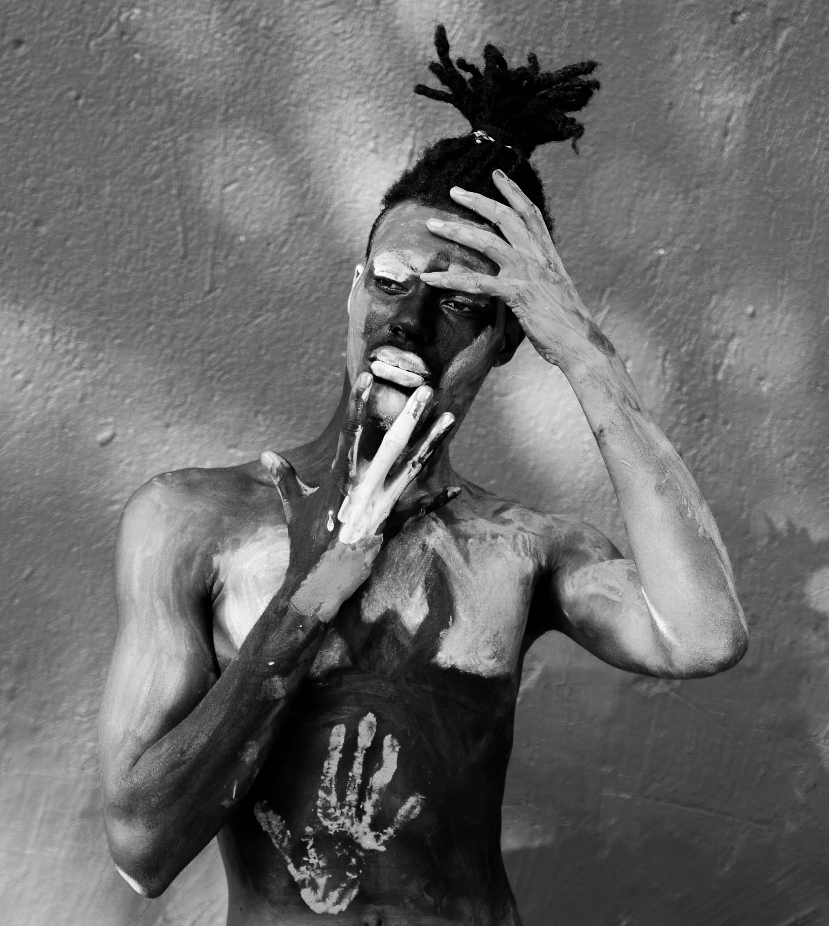 a shirtless man with body paint posing with hands on face